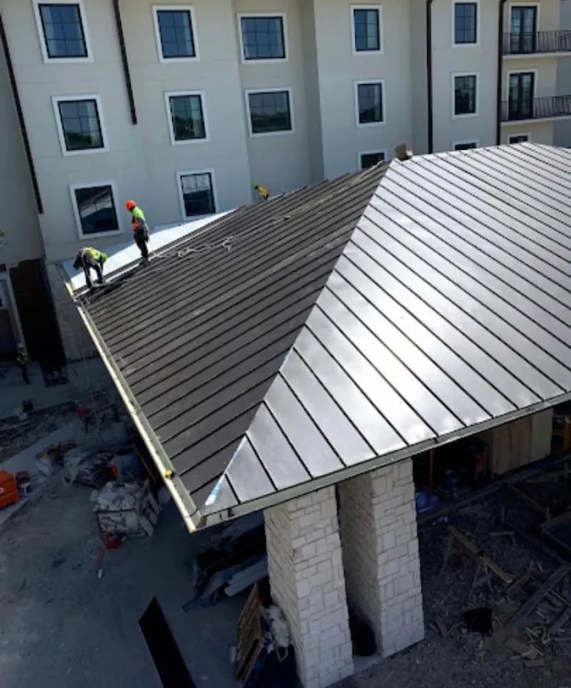 Crew installing standing seam metal roof panels on a commercial project in Vancleave